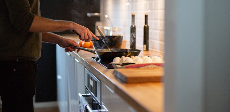 En man står vid spisen och lagar pannkakor
