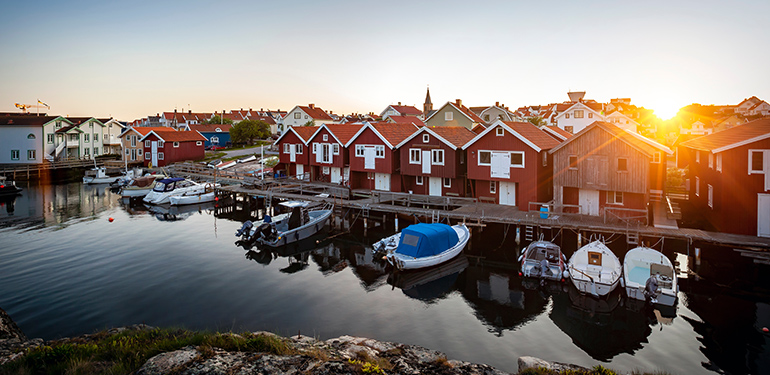 Små röda trähus och båtbrygga på västkusten