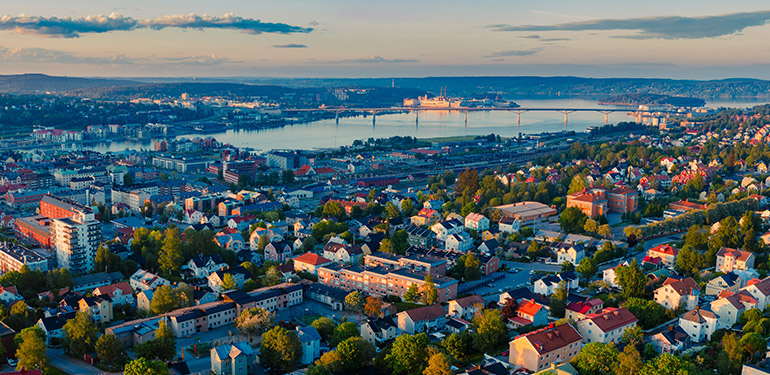 Flygfoto över stad med flerbostadshus, bro över sjö i horisonten