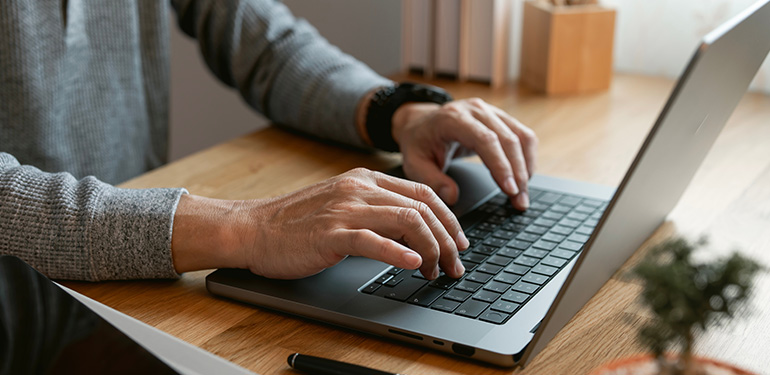 En man skriver på ett tangentbord, endast armarna i bild