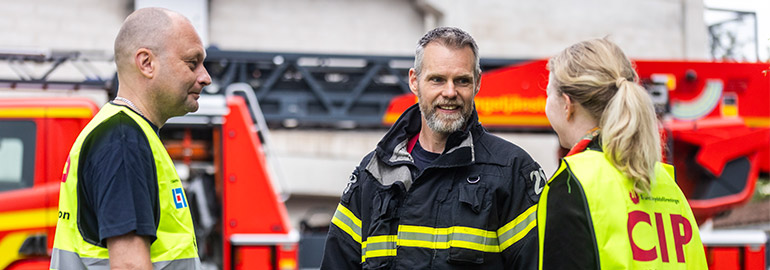 Man från räddningstjänsten pratar med två civila insatspersoner