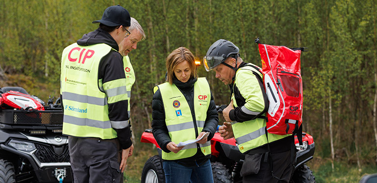 Fyra civila insatspersoner står tillsammans och diskuterar något vid en olycksplats