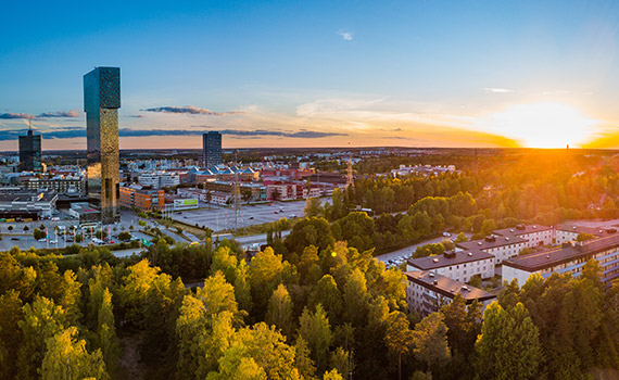 Stadsmiljö i solnedgången med både höghus och grönskande områden