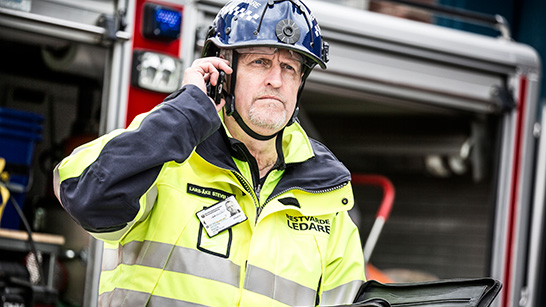 Restvärdeledare som står framför en brandbil och pratar i telefon