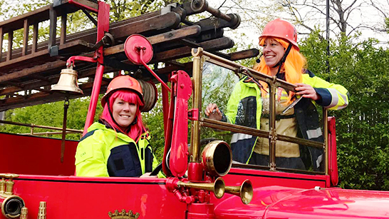 Camilla Andersson och Cina Nilsson med skyddskläder i en brandbil