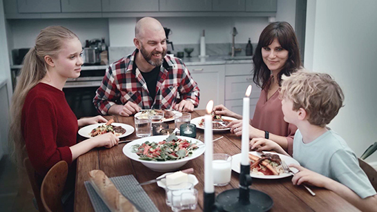 Familj sitter vid ett dukat bord och skrattar