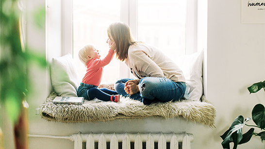 Kvinna och barn sitter mittemot varandra vid ett fönster