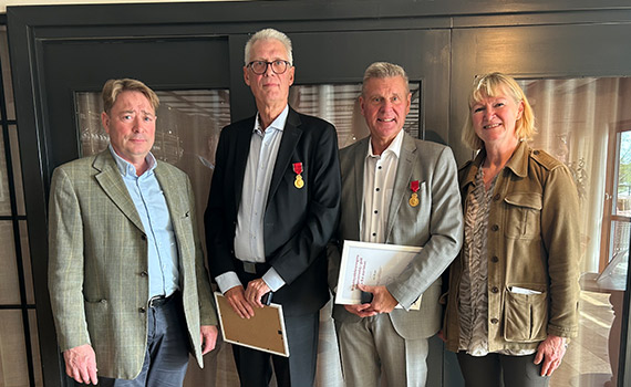 Två förtjänstmedaljörer visar upp medaljer och diplom mellan Brandskyddsföreningens generalsekreterare och styrelseordförande