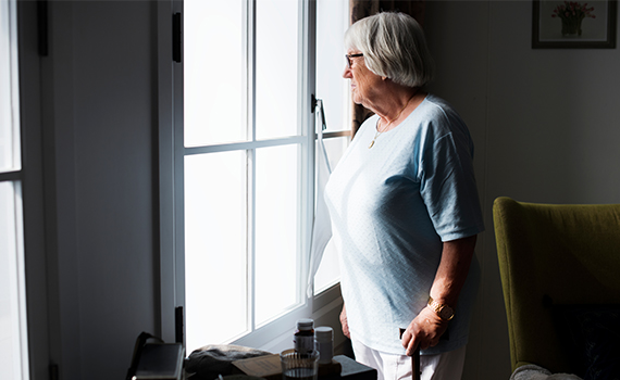 En äldre kvinna som ser ut genom ett fönster