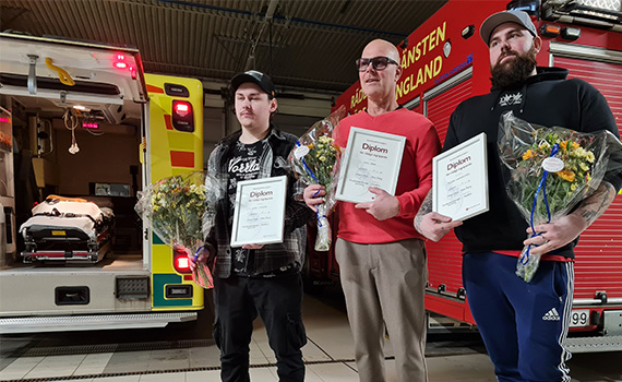 Tre personer framför utryckningsfordon