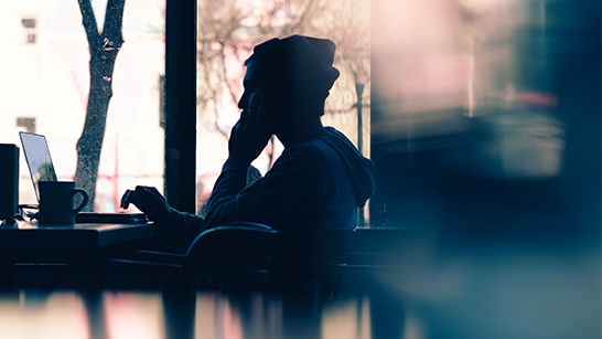 Person pratar i telefon och sitter vid datorn