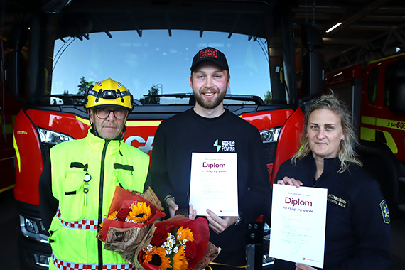 Tre personer framför en brandbil