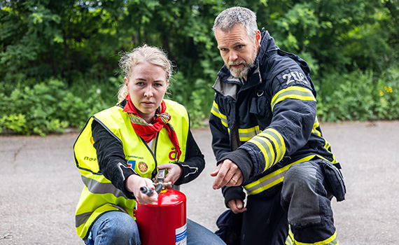 En brandman lär en civil insatsperson hur man använder en brandsläckare