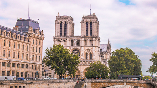 Notre Dame bakom träd och bredvid en annan byggnad