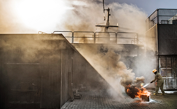 Någon släcker en liten brand ombord på ett rökfyllt fartyg