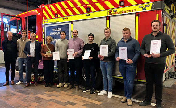 Personer med diplom framför en brandbil