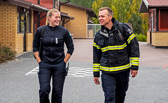 Två personer från räddningstjänsten pratar med varandra på en skolgård